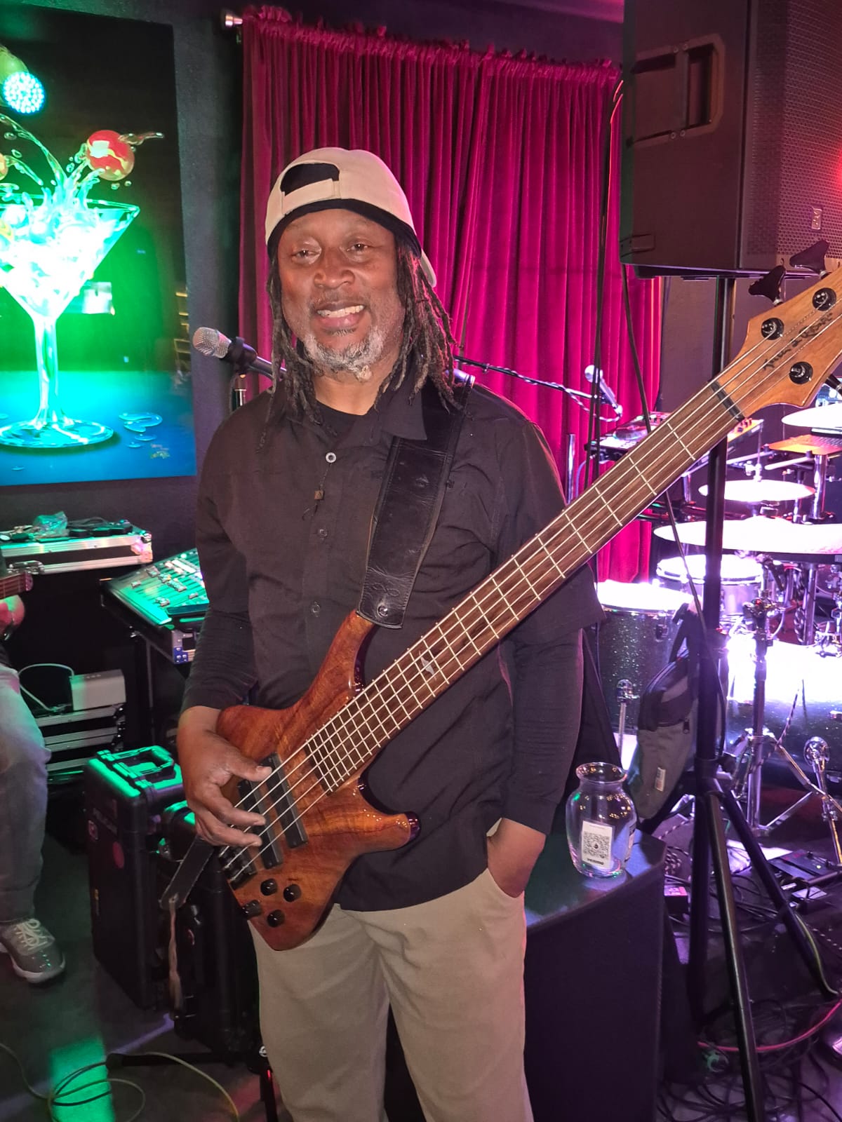 Man playing bass guitar on stage with vibrant lighting.